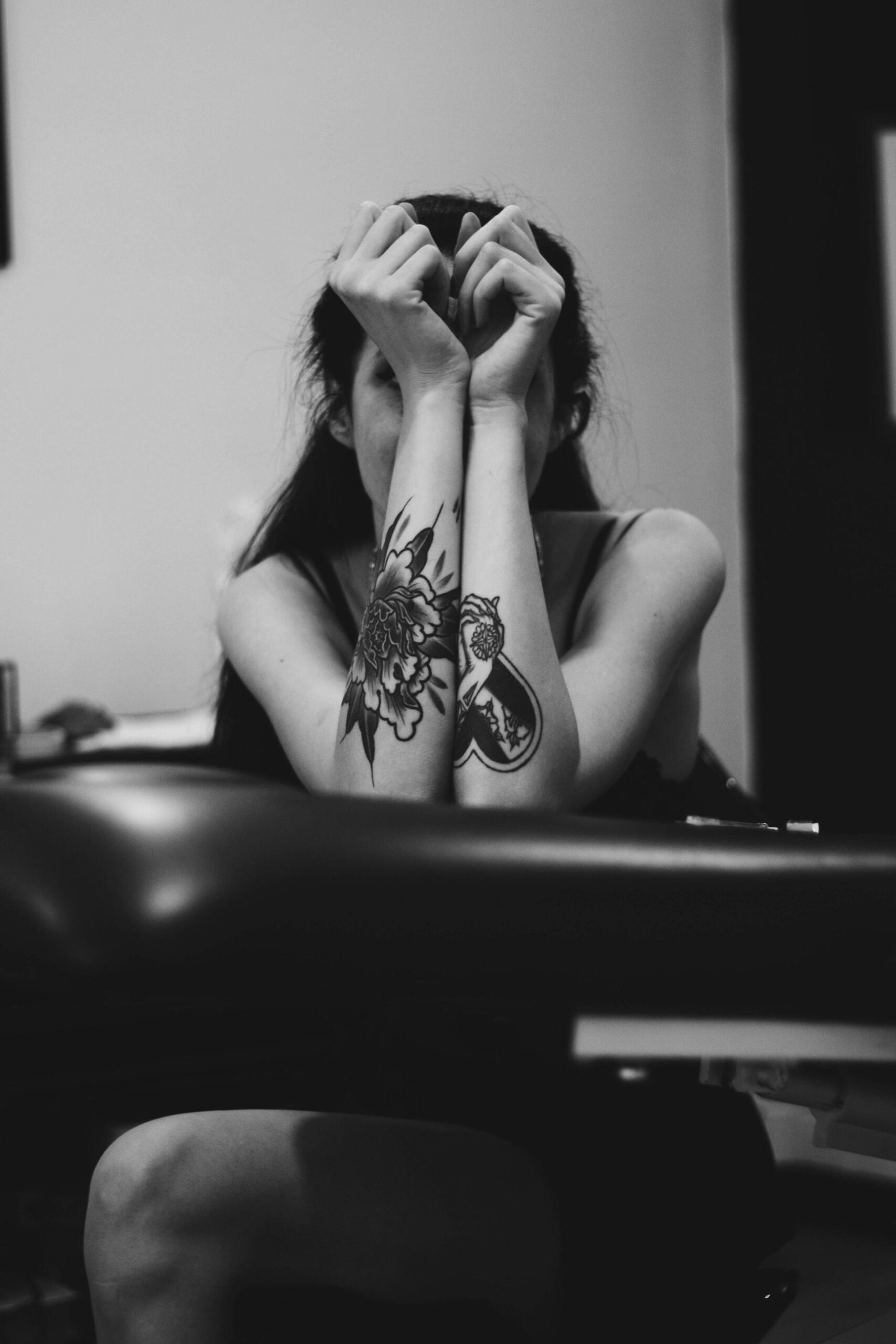 a person with tattoos hiding behind her arms